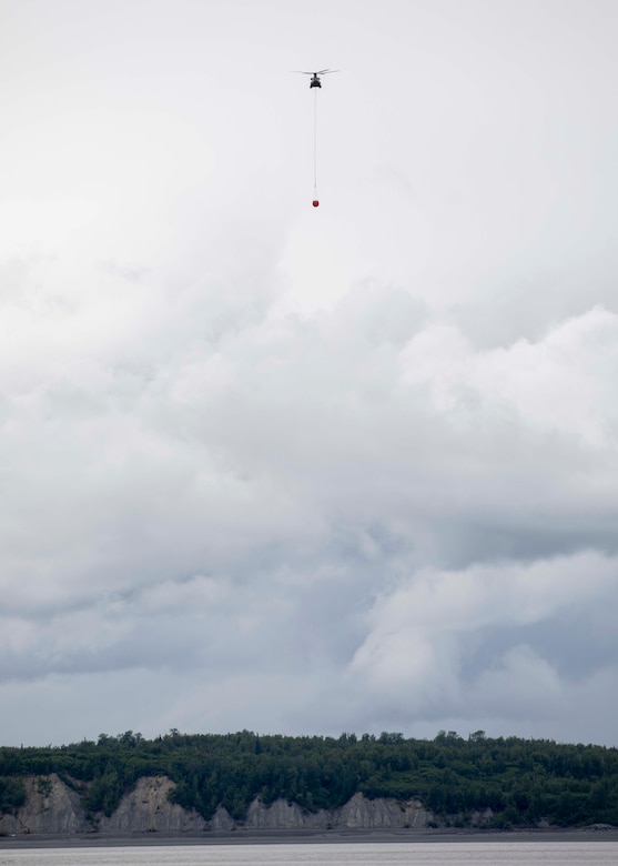 A 1st Battalion, 207th Aviation Regiment CH-47 Chinook helicopter with a Bambi water bucket system attached flies overhead during the unit's Red Card certification on Joint Base Elmendorf-Richardson, June 9, 2021. Red Card certification, also known as the Incident Qualification Card, is an accepted interagency certification that a person is qualified in order to accomplish the required mission when arriving on an incident. For 1-207th AVN pilots, this certification means proficiency in water bucket drops to assist with wildfire emergencies within the state. (U.S. Army National Guard photo by Spc. Grace Nechanicky)