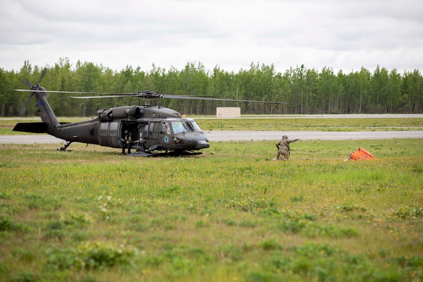 Pilots and crew members of the 207th Aviation Battalion attach a Bambi water bucket system to a UH-60 Black Hawk helicopter to complete their Red Card certification on Joint Base Elmendorf-Richardson, June 9, 2021. Red Card certification, also known as the Incident Qualification Card, is an accepted interagency certification that a person is qualified in order to accomplish the required mission when arriving on an incident. For 1-207th AVN pilots, this certification means proficiency in water bucket drops to assist with wildfire emergencies within the state. (U.S. Army National Guard photo by Spc. Grace Nechanicky)