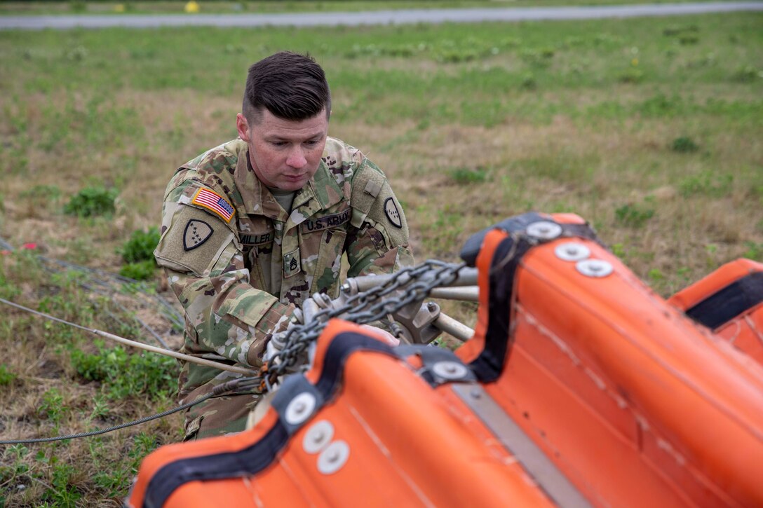 Staff Sgt. Kurt Miller, a crew chief with 1st Battalion, 207th Aviation Regiment, prepares a Bambi water bucket system to be attached to a UH-60 Black Hawk helicopter for the unit’s Red Card certification on Joint Base Elmendorf-Richardson, June 9, 2021. Red Card certification, also known as the Incident Qualification Card, is an accepted interagency certification that a person is qualified in order to accomplish the required mission when arriving on an incident. For 1-207th AVN pilots, this certification means proficiency in water bucket drops to assist with wildfire emergencies within the state. (U.S. Army National Guard photo by Spc. Grace Nechanicky)