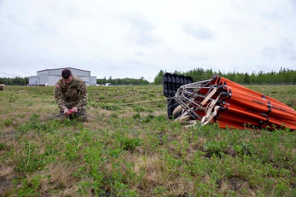 Staff Sgt. Kurt Miller, a crew chief with 1st Battalion, 207th Aviation Regiment, prepares a Bambi water bucket system to be attached to a UH-60 Black Hawk helicopter for the unit’s Red Card certification on Joint Base Elmendorf-Richardson, June 9, 2021. Red Card certification, also known as the Incident Qualification Card, is an accepted interagency certification that a person is qualified in order to accomplish the required mission when arriving on an incident. For 1-207th AVN pilots, this certification means proficiency in water bucket drops to assist with wildfire emergencies within the state. (U.S. Army National Guard photo by Spc. Grace Nechanicky)