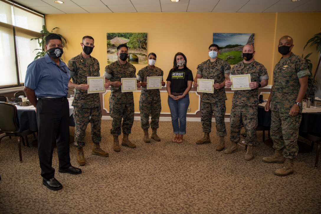 U.S. Marines, Sailors, and SOFA status civilians with 3rd Marine Expeditionary Brigade pose for group photo during a Reboot graduation on Camp Courtney, Okinawa, Japan, June 3, 2021. Reboot Recovery is a Christian non-profit organization that holds 12-week courses to help service members overcome trauma from post-traumatic stress.
