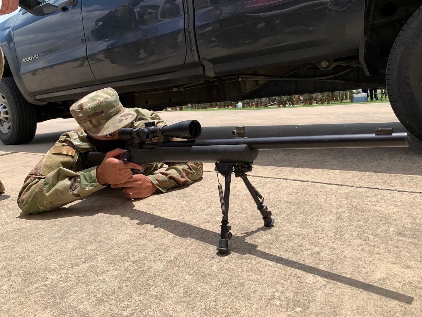 Airman lying on ground looking through rifle scope.
