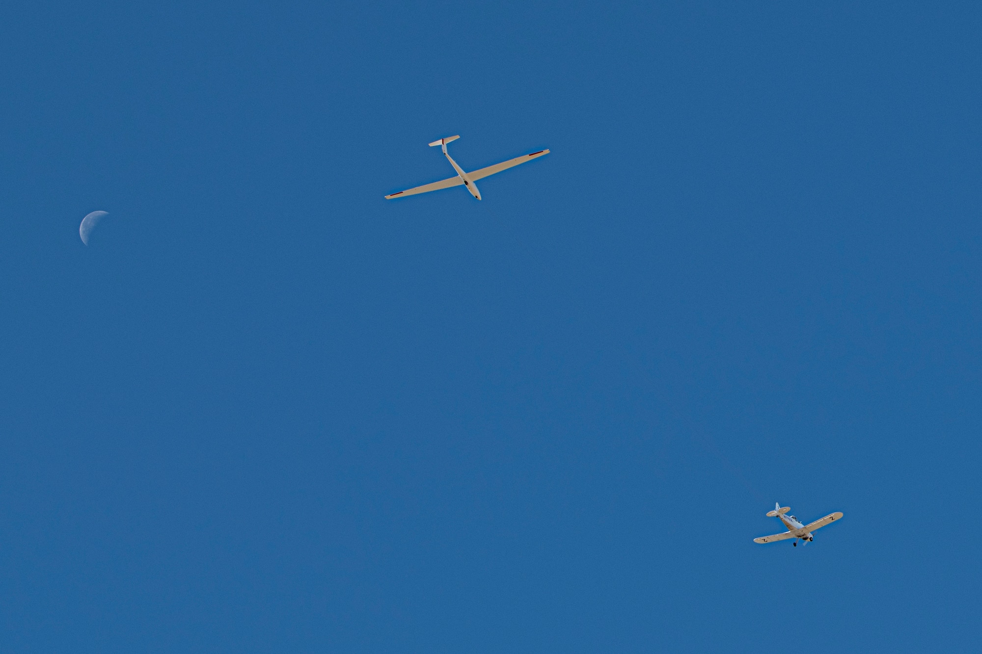Glider being towed by plane with moon in background