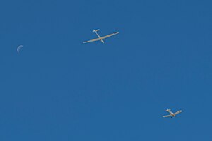 Glider being towed by plane with moon in background