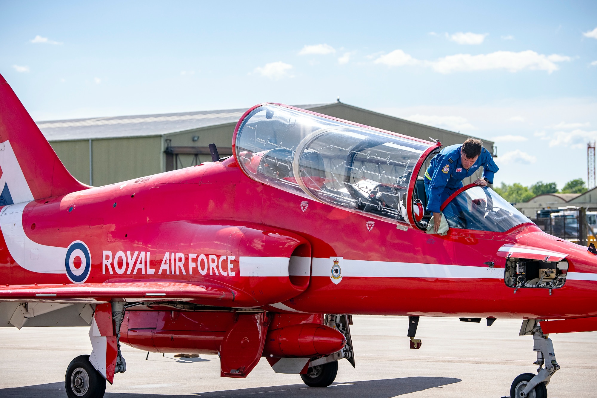 Flight Lieutenant Joe Fallon, Red Arrows Junior Engineering officer, wipes down a Hawk T1 aircraft at RAF Fairford, England, June 4, 2021. The Red Arrows landed at Fairford to refuel in preparation for the Midlands Air Festival. (U.S. Air Force photo by Senior Airman Eugene Oliver)
