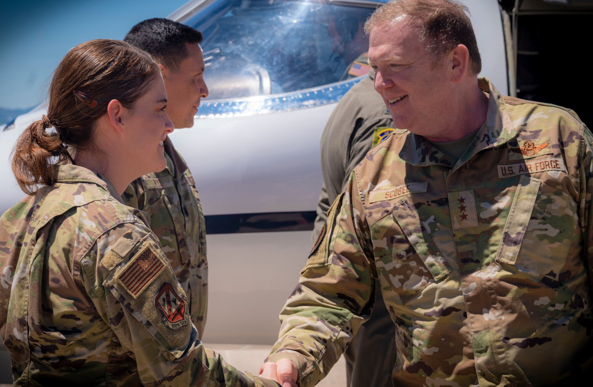 A photo of a woman shaking hands with a man near the front of an aircraft.