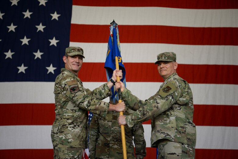 Two commanders pose for a photo during a ceremony.