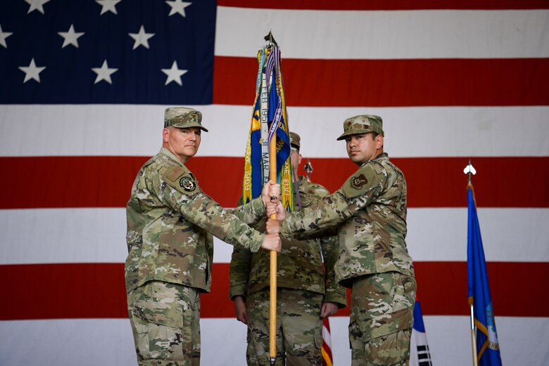Two commanders pose for a photo during a ceremony.
