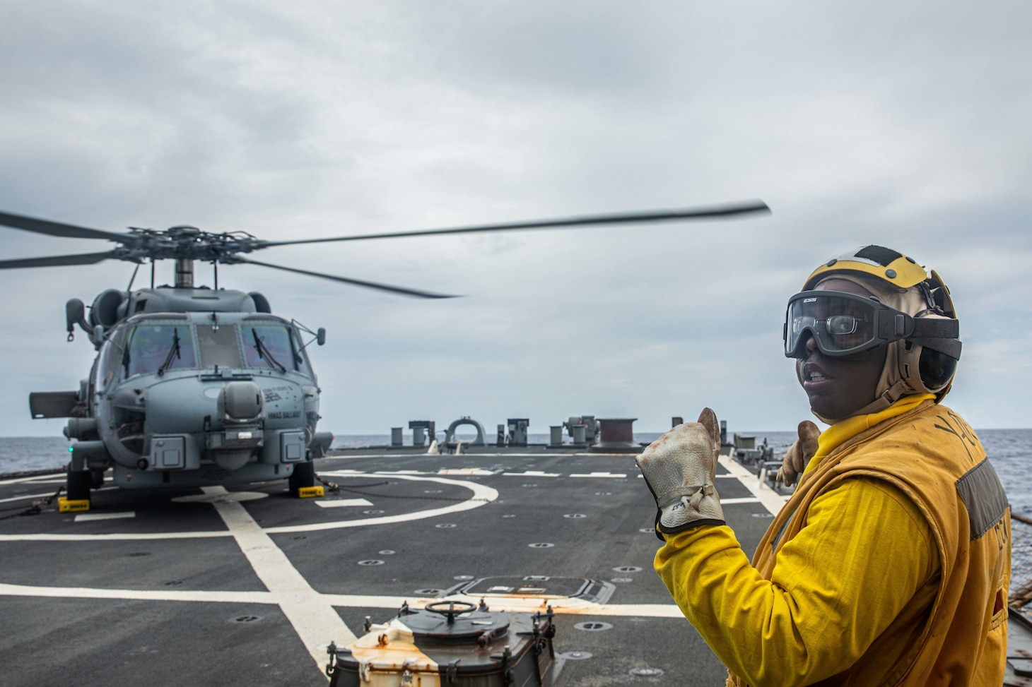 Boatswain’s Mate 2nd Class Daniel Branham, from Dalton, Ga., signals to an MH-60R Sea Hawk assigned to the Royal Australian Navy Anzac-class frigate HMAS Ballarat (FFH 155) on the flight deck of Arleigh Burke-class guided-missile destroyer USS Curtis Wilbur (DDG 54). Curtis Wilbur is assigned to Commander, Task Force 71/Destroyer Squadron (DESRON) 15, the Navy’s largest forward-deployed DESRON and U.S. 7th Fleet’s principal surface force. (U.S. Navy photo by Mass Communication Specialist 3rd Class Zenaida Roth)
