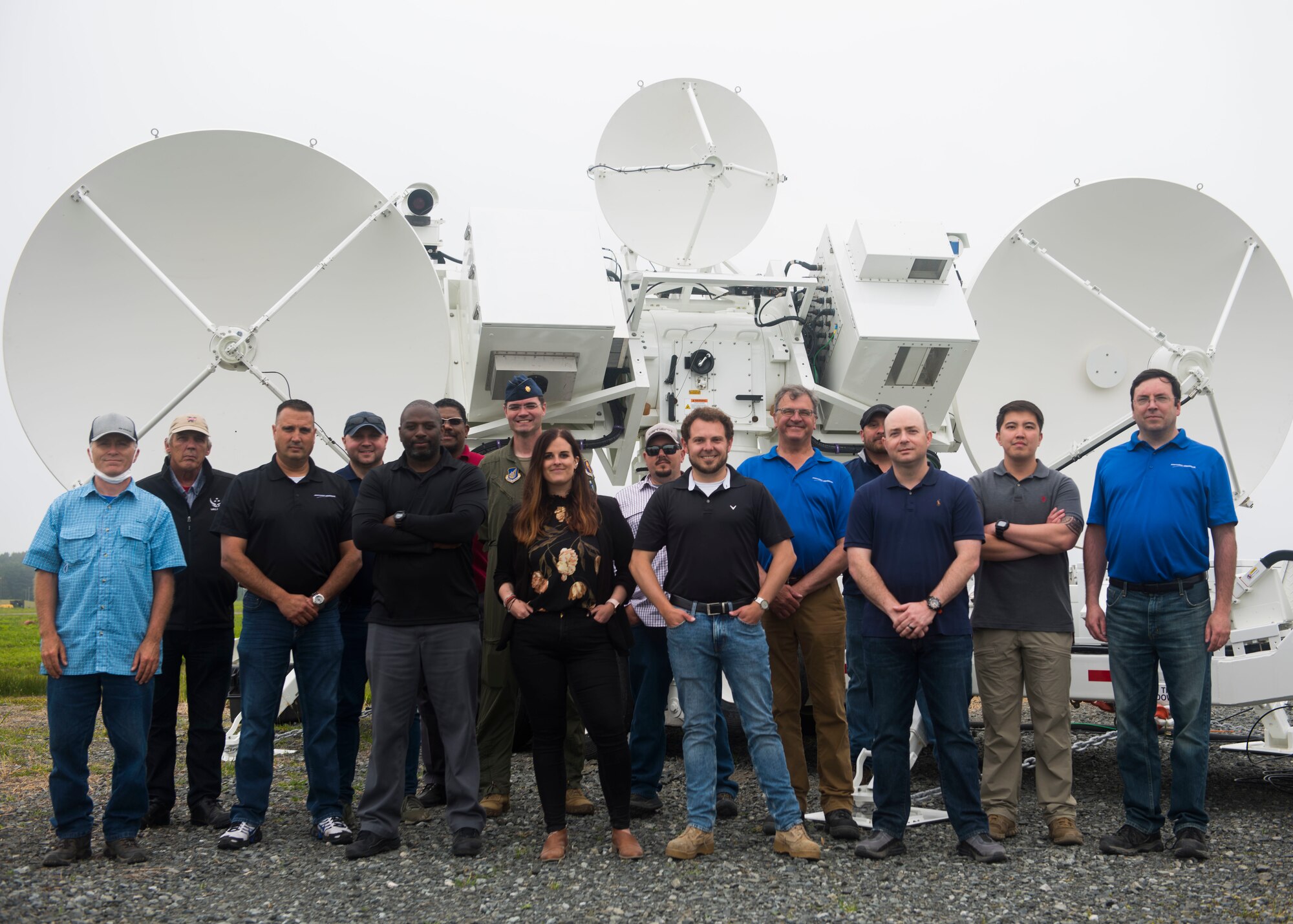 Group of men and women pose for a photo in front of a Joint Threat Emitter