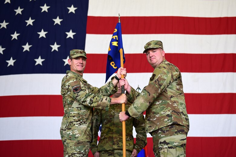 Two commanders pose for a photo during a ceremony.