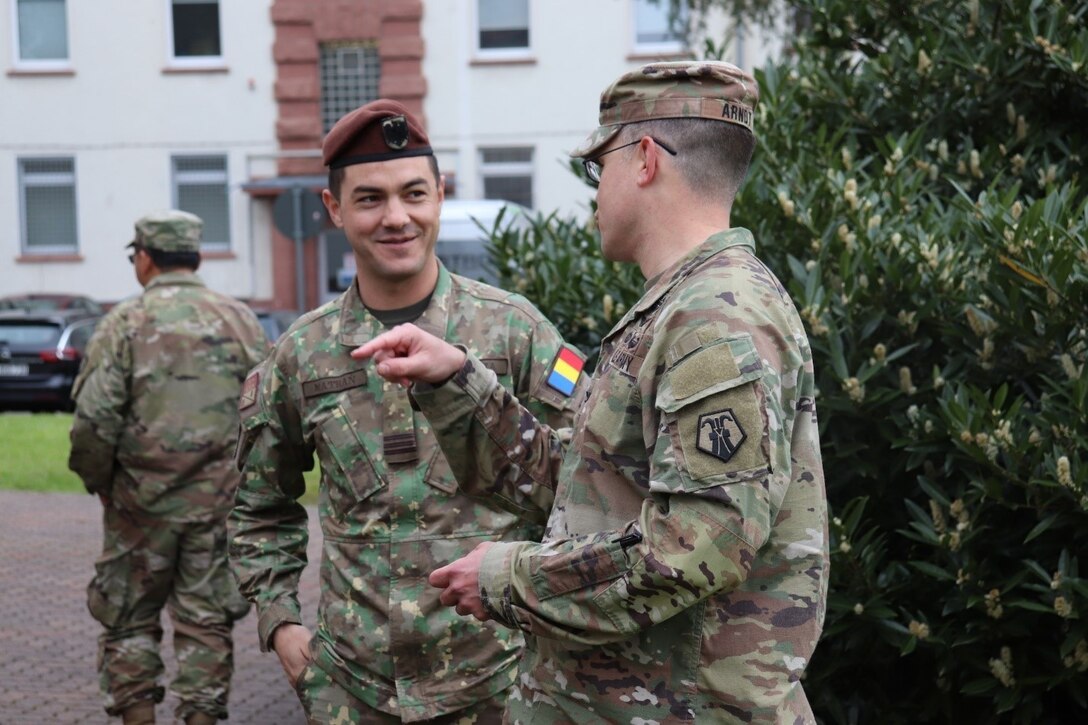U.S. Army Reserve Col. Jason Ardnt, chief of staff of the 7th Mission Support Command and deputy joint security coordinator for the Joint Security Coordination Center, speaks with Romanian military police officer Capt. Razvan Matran on Panzer Kaserne in Kaiserslautern, Germany, May 27, 2021. U.S. Army Reserve Soldiers and Civilians assigned to the 7th MSC teamed up with NATO Allies and partners from 18 different countries to provide a unique protection capability for U.S. Army Europe and Africa by serving as the JSCC in support of DEFENDER Europe 21. (U.S. Army Reserve Photo by Capt. Lorenzo Llorente)