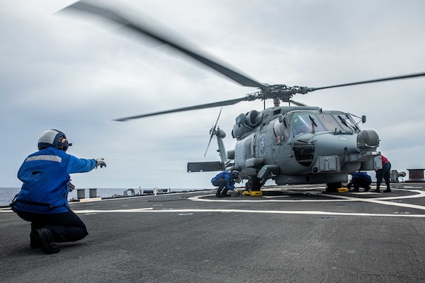 Sailors aboard Arleigh Burke-class guided-missile destroyer USS Curtis Wilbur (DDG 54) chock and chain a MH-60R Sea Hawk assigned to the Royal Australian Navy Anzac-class frigate HMAS Ballarat (FFH 155) on the flight deck. Curtis Wilbur is assigned to Commander, Task Force 71/Destroyer Squadron (DESRON) 15, the Navy’s largest forward-deployed DESRON and U.S. 7th Fleet’s principal surface force. (U.S. Navy photo by Mass Communication Specialist 3rd Class Zenaida Roth)