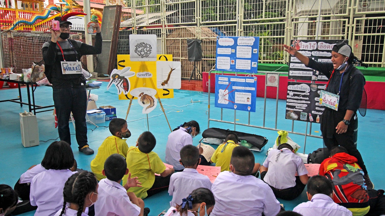 Insectary staff in mosquito costumes in front of a group of school children.