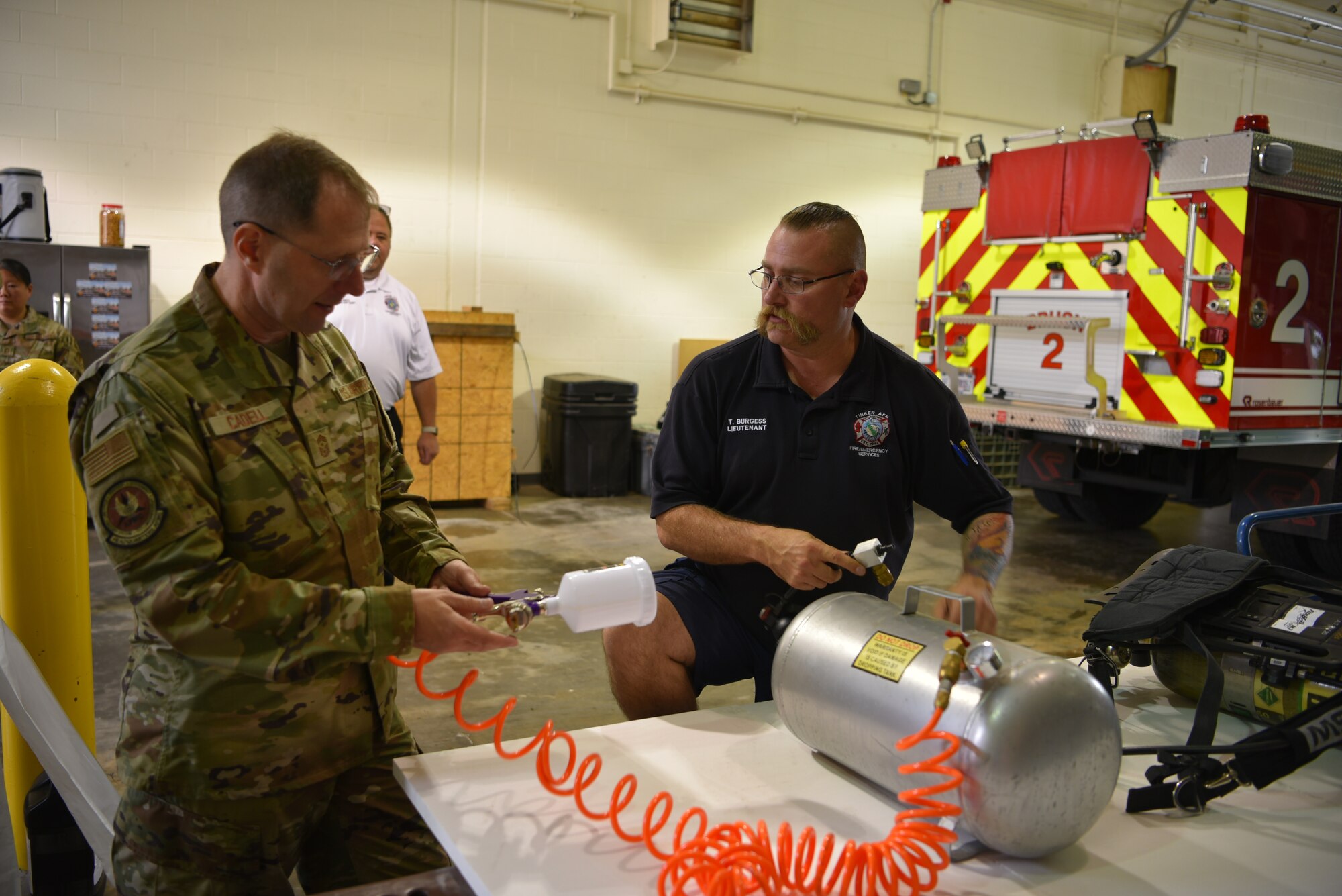 Chief Cadell looking at sprayer with Lt. Burgess