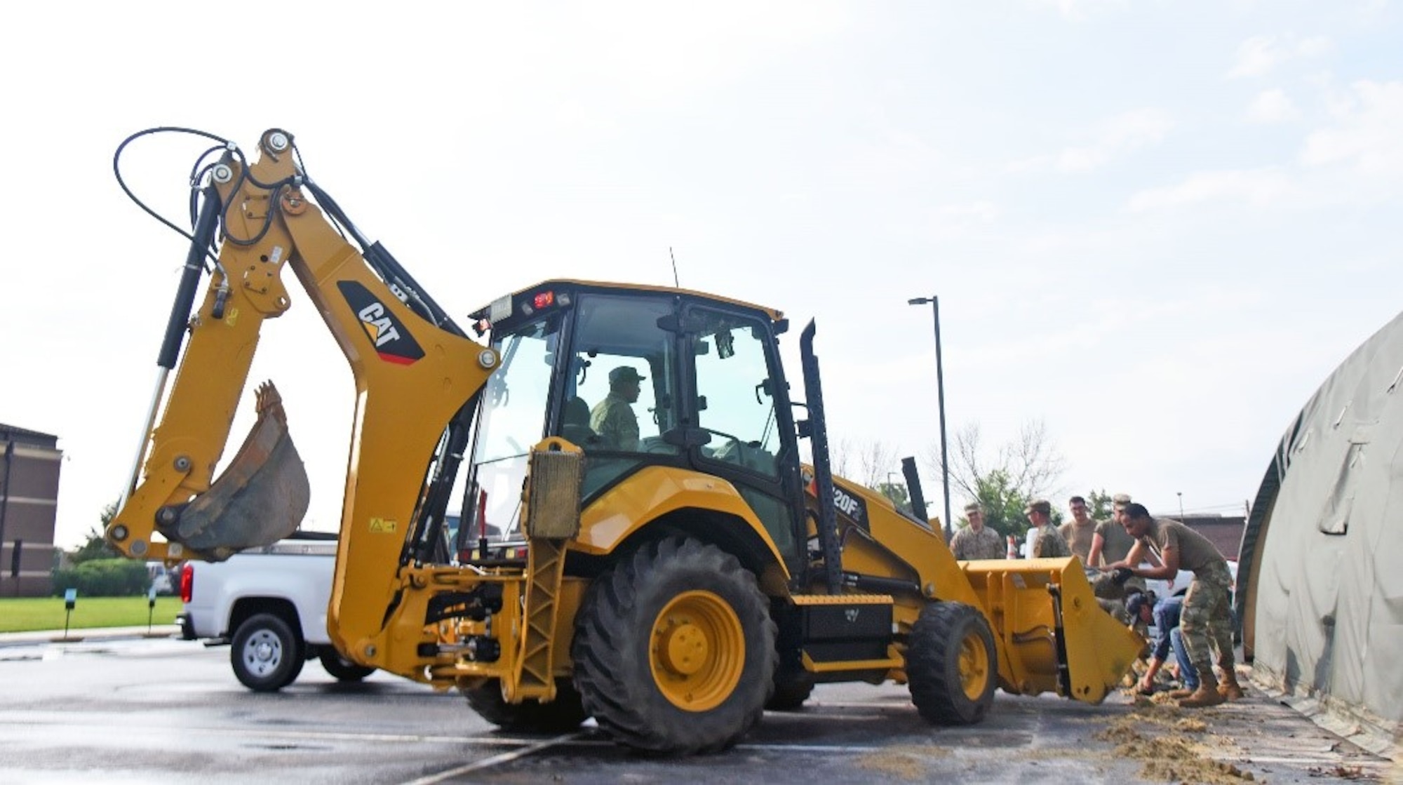 Airmen from 87th Civil Engineering Squadron are placing sandbags into the bulldozer outside the 87th Medical Group facility, June 10th, 2021, on Joint Base McGuire-Dix-Lakehurst, N.J. The sandbags were used as extra weight to keep the tents grounded, protect them from strong winds and other hazardous weather conditions. (U.S. Air Force photo by Daniel Barney)