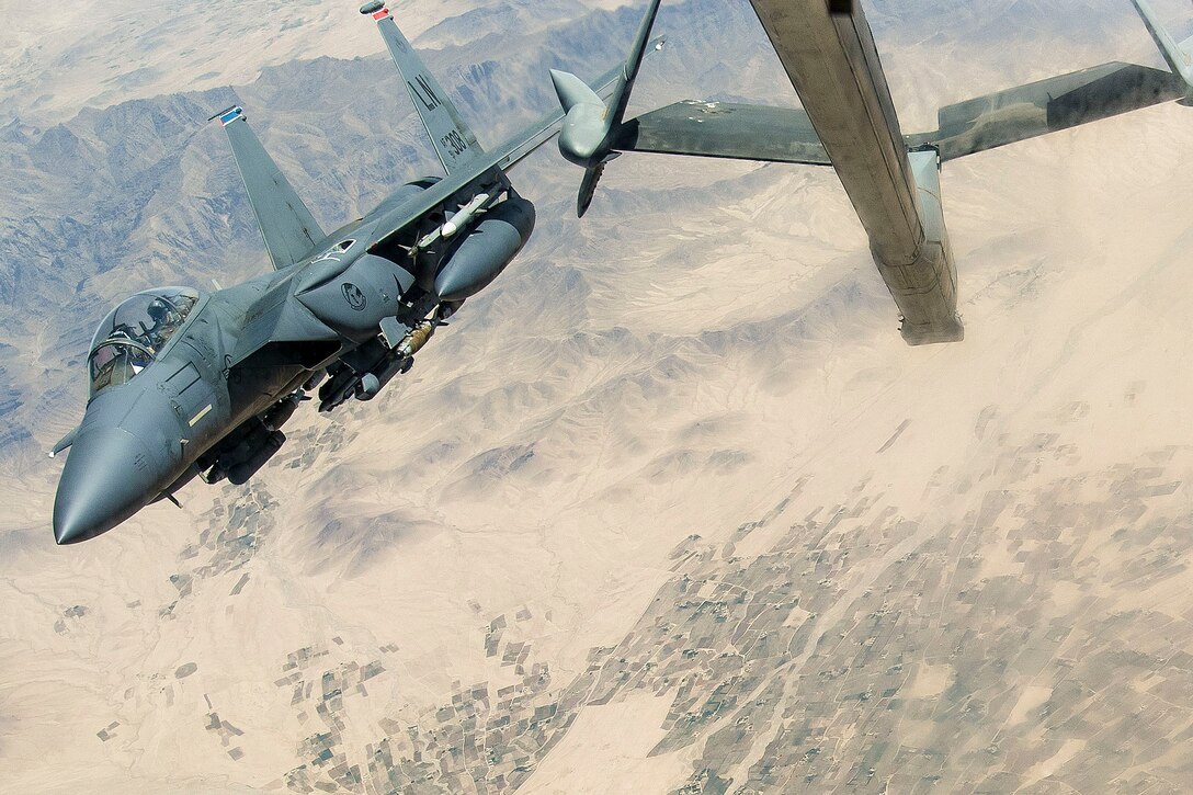 A jet flies next to a large aircraft.