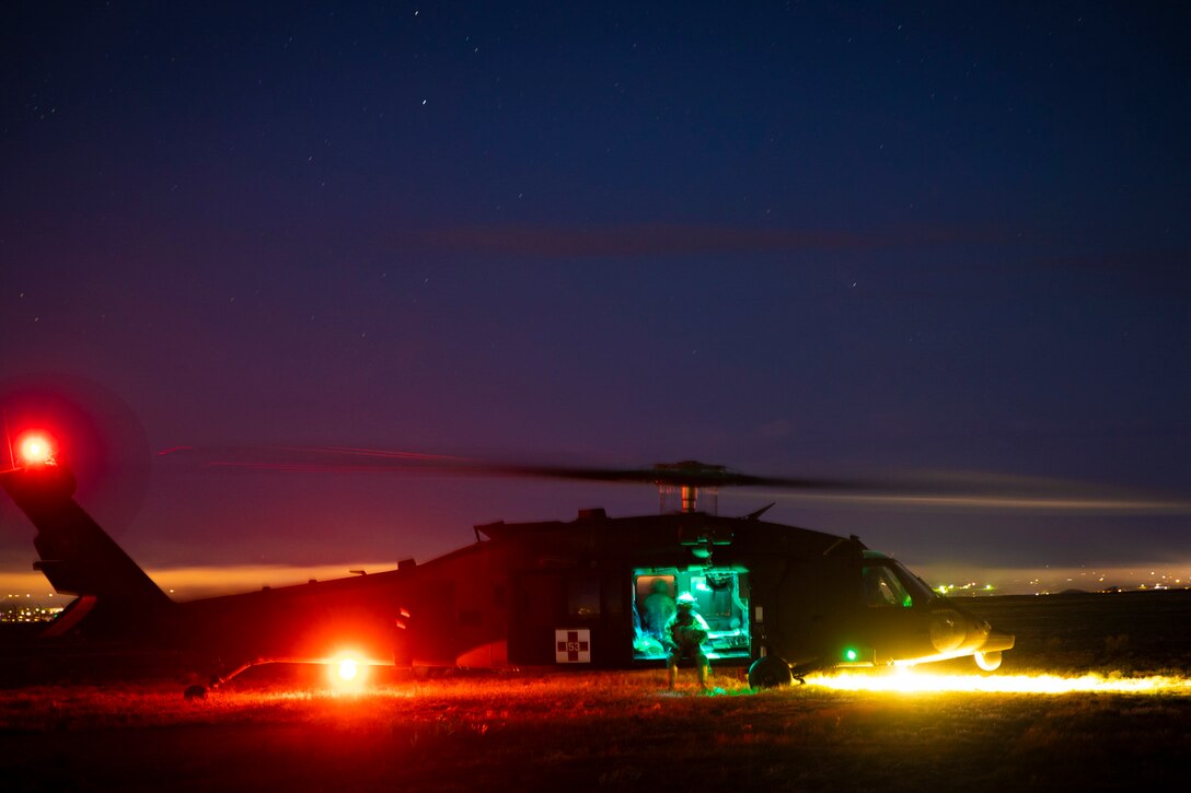 Soldiers sit inside a parked helicopter at night.