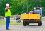 A man directs a tractor holding a used cabinet.