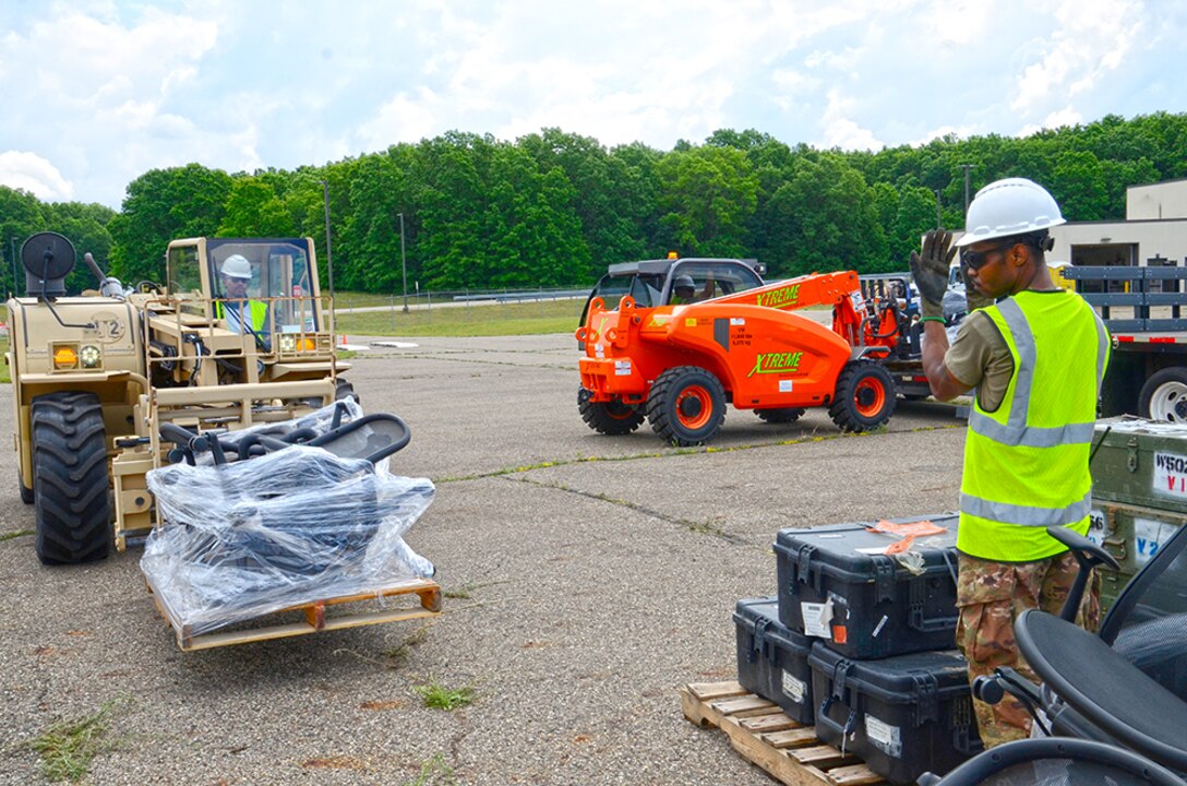 A man directs another man operating a forklift.