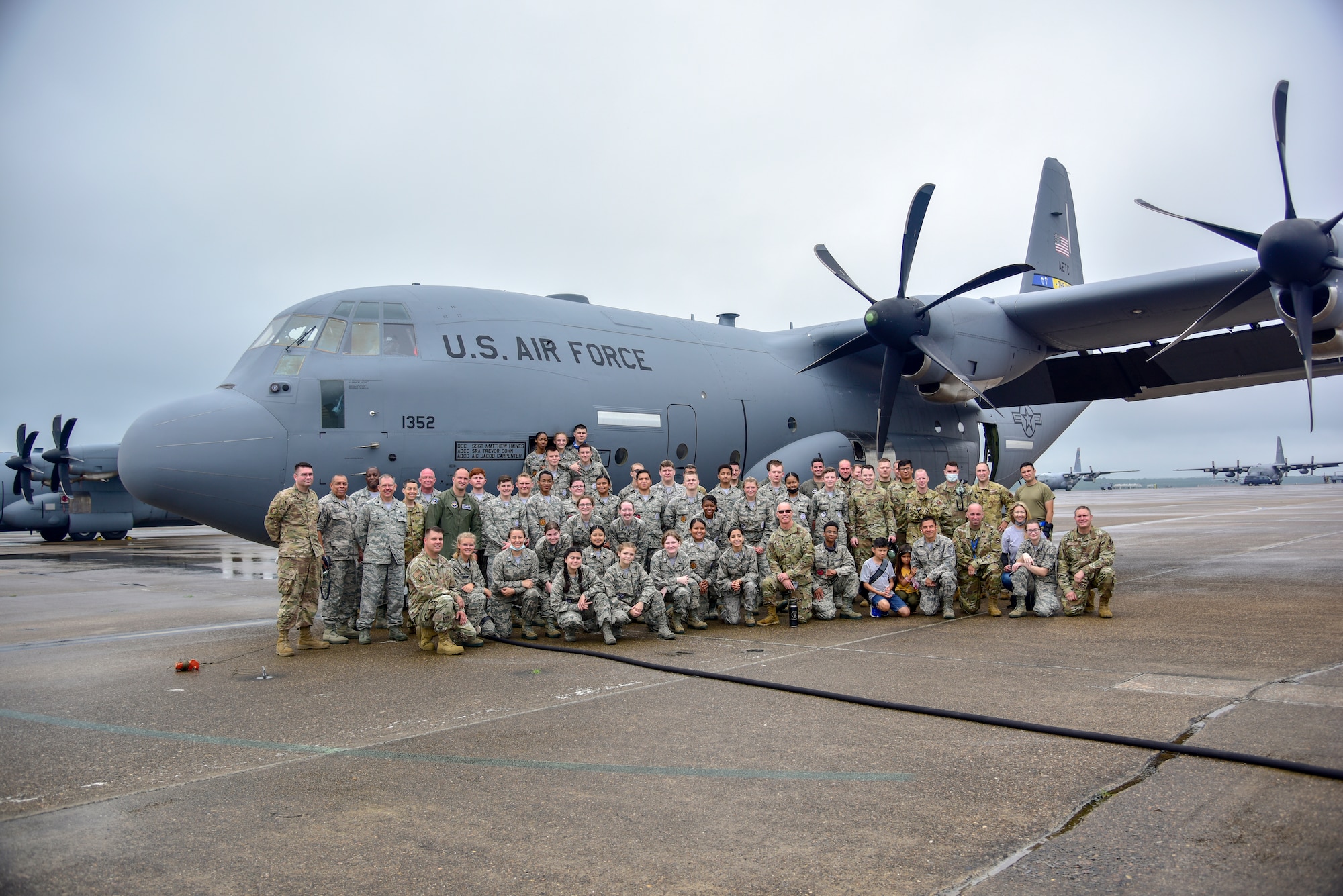 Airmen and Junior ROTC cadets pose for a photo with an aircraft.