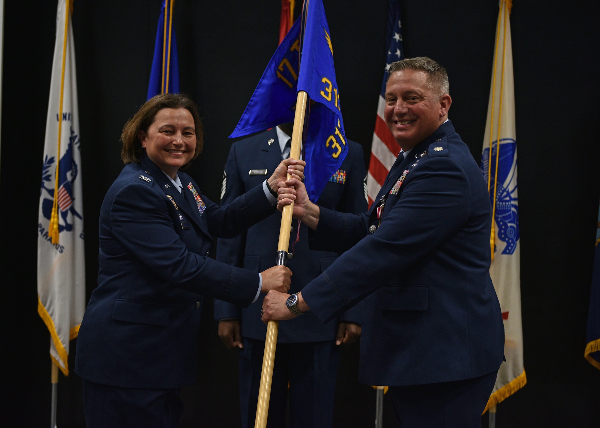 U.S. Air Force Col. Angelina Maguinness, 17th Training Group commander, takes the guidon from Lt. Col. Herbert Millet III , outgoing 313th Training Squadron commander, during the change of command ceremony at the Event Center on Goodfellow Air Force Base, Texas, June 11, 2021. Millet is leaving to attend senior development education at the Air War College at Maxwell Air Force Base, Alabama. (U.S. Air Force photo by Senior Airman Ashley Thrash)