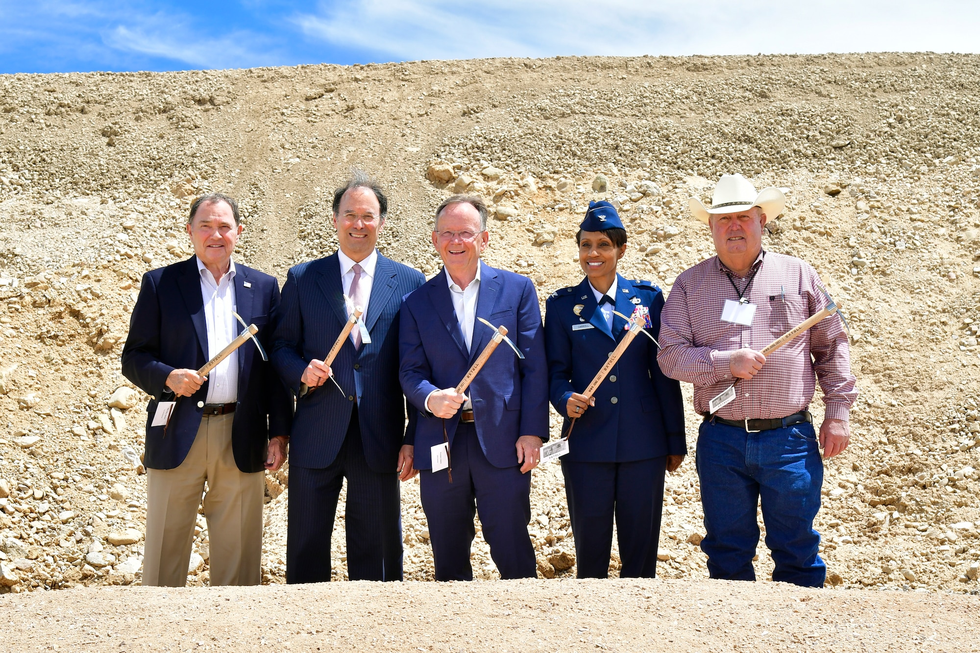A group photo of ground breaking participants holding up a ceremonial pick axe.