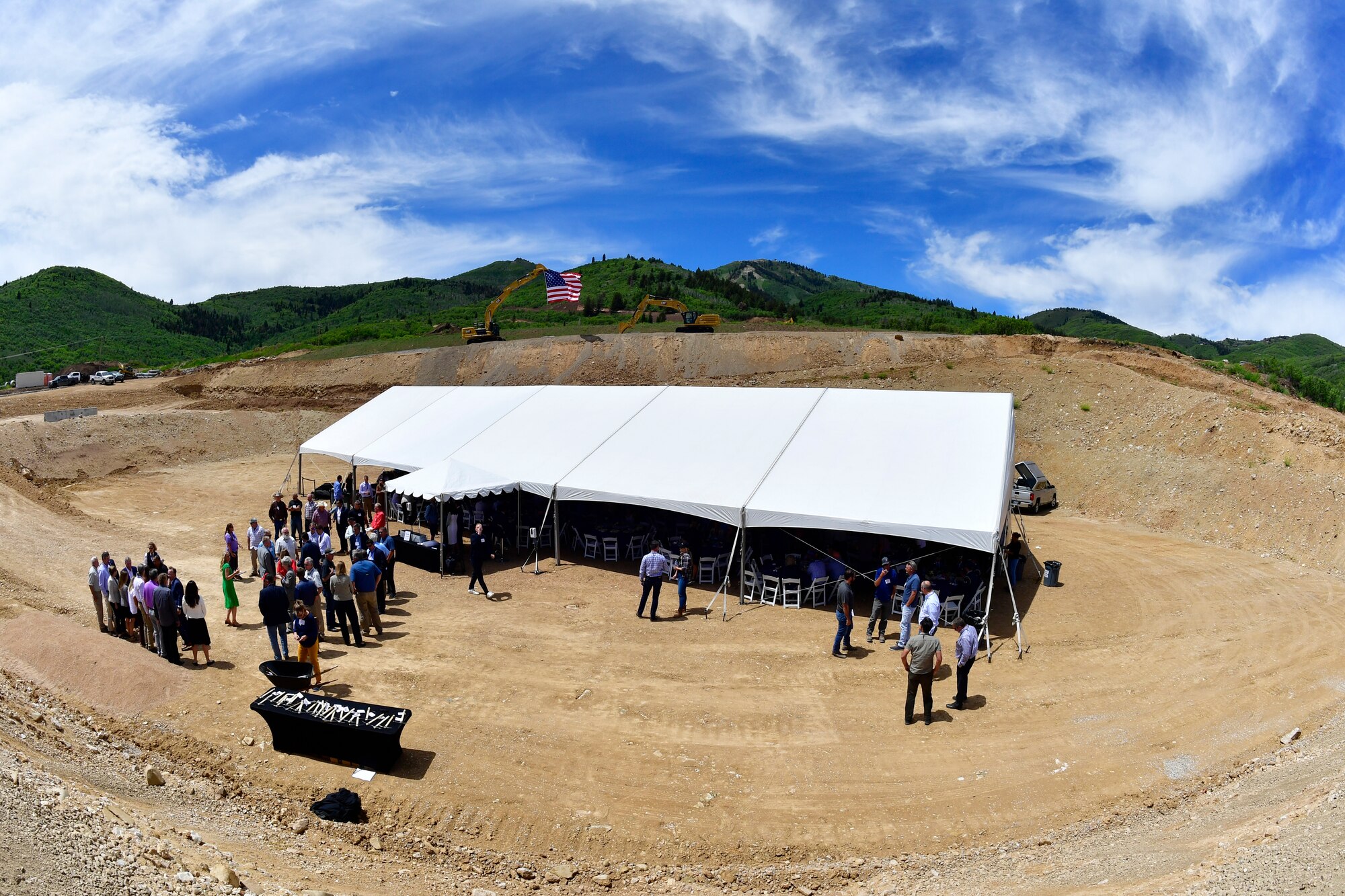 A picture of a tent and attendees on an excavated parcel of land at the ground breaking ceremony.
