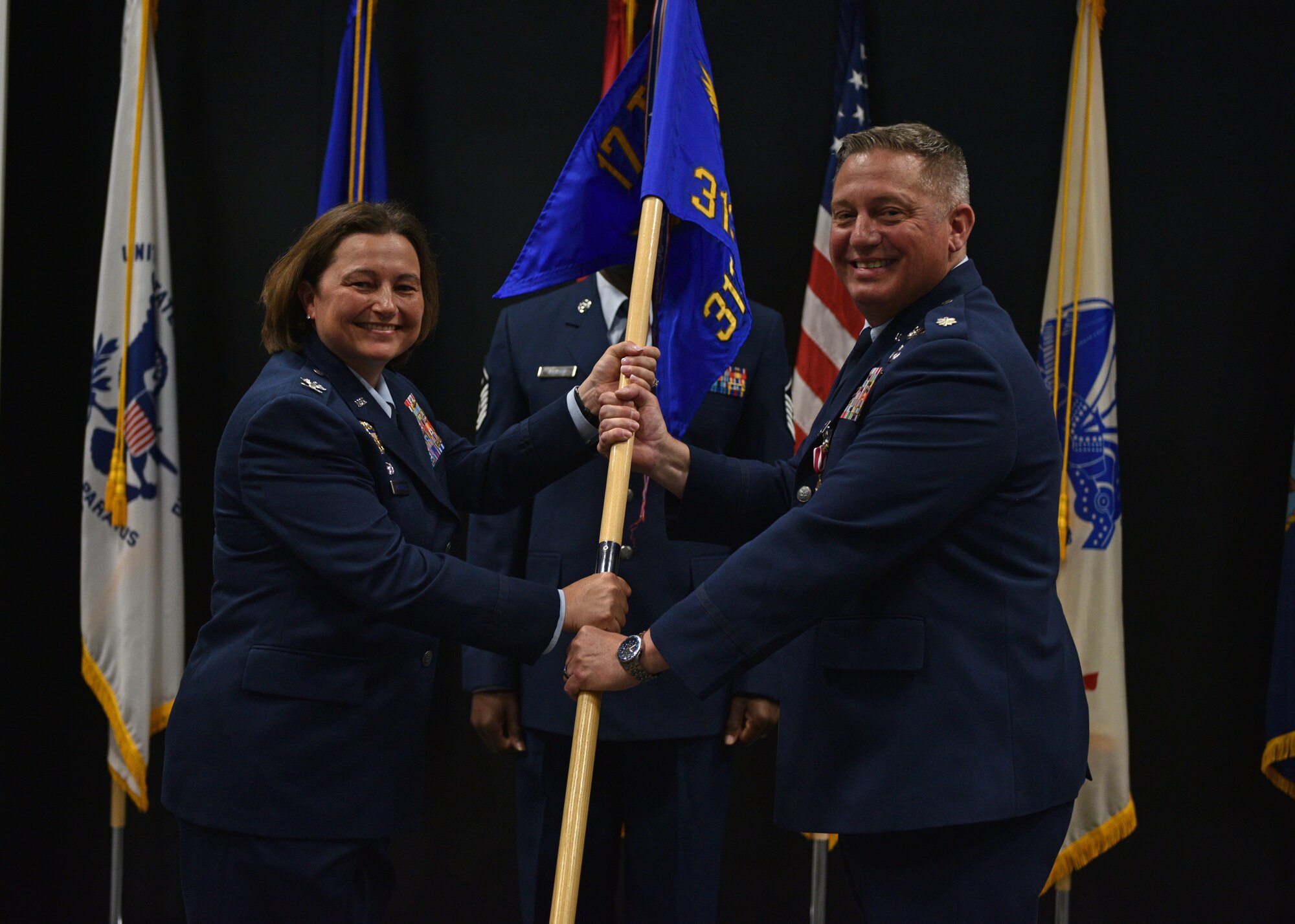 U.S. Air Force Col. Angelina Maguinness, 17th Training Group commander, takes the guidon from Lt. Col. Herbert Millet III , outgoing 313th Training Squadron commander, during the change of command ceremony at the Event Center on Goodfellow Air Force Base, Texas, June 11, 2021. Millet is leaving to attend senior development education at the Air War College at Maxwell Air Force Base, Alabama. (U.S. Air Force photo by Senior Airman Ashley Thrash)