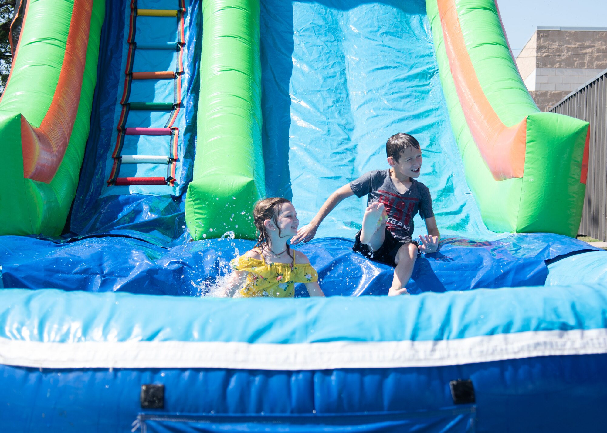 Dependents from Goodfellow Air Force Base play on an inflatable water slide during the 17th Force Support Squadron Block Party, on Goodfellow AFB, Texas. The event featured more than 10 different events inducing games and music. (U.S. Air Force photo by Staff Sgt. Tyrell Hall)