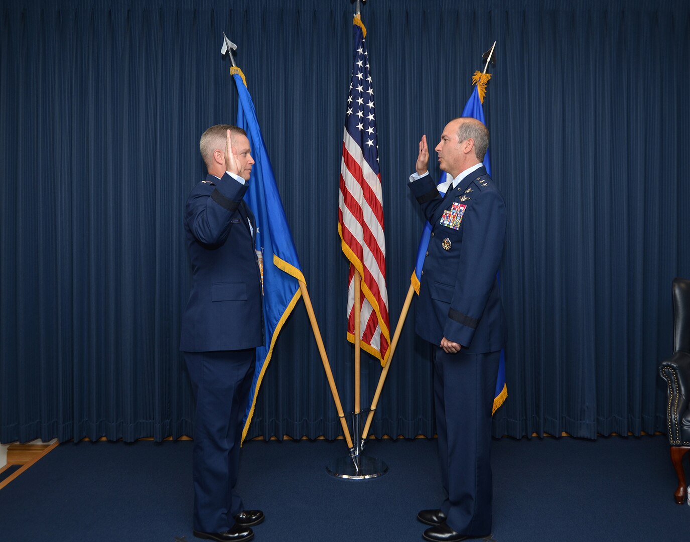 Two Airmen in dress uniform hold up right hands during the Oath of Office.