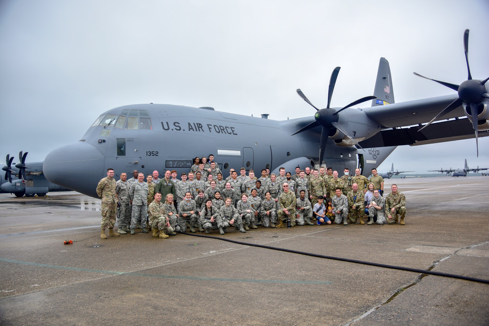 Airmen and Junior ROTC cadets pose for a photo with an aircraft.