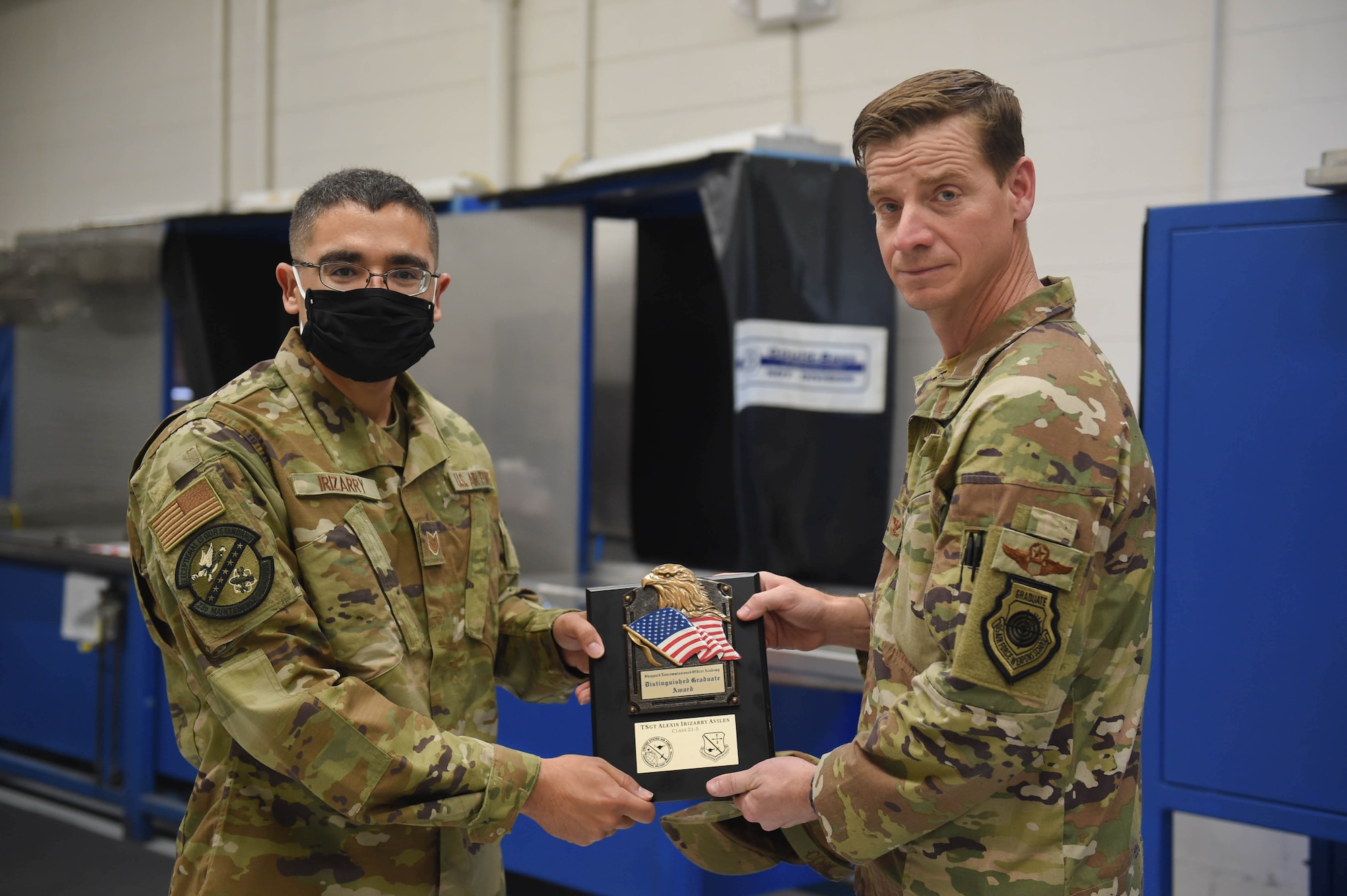 Two service members holding an award