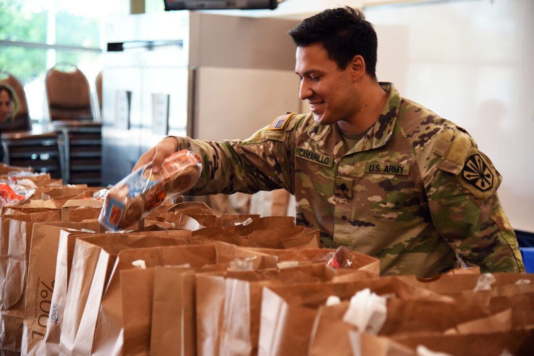 A soldier prepares bags of groceries that will be delivered to residents at a senior center.