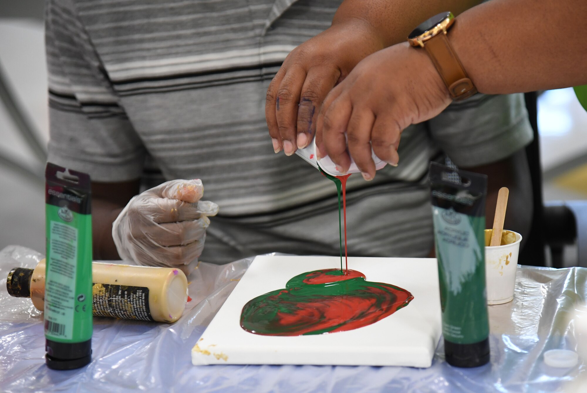 Shelena Gray, 81st Force Support Squadron teen coordinator, pours acrylic paints onto a canvas during the Keesler Youth Center fine arts camp at Keesler Air Force Base, Mississippi, June 10, 2021. The youth center offers a variety of camps throughout the summer for children of military personnel. (U.S. Air Force photo by Kemberly Groue)
