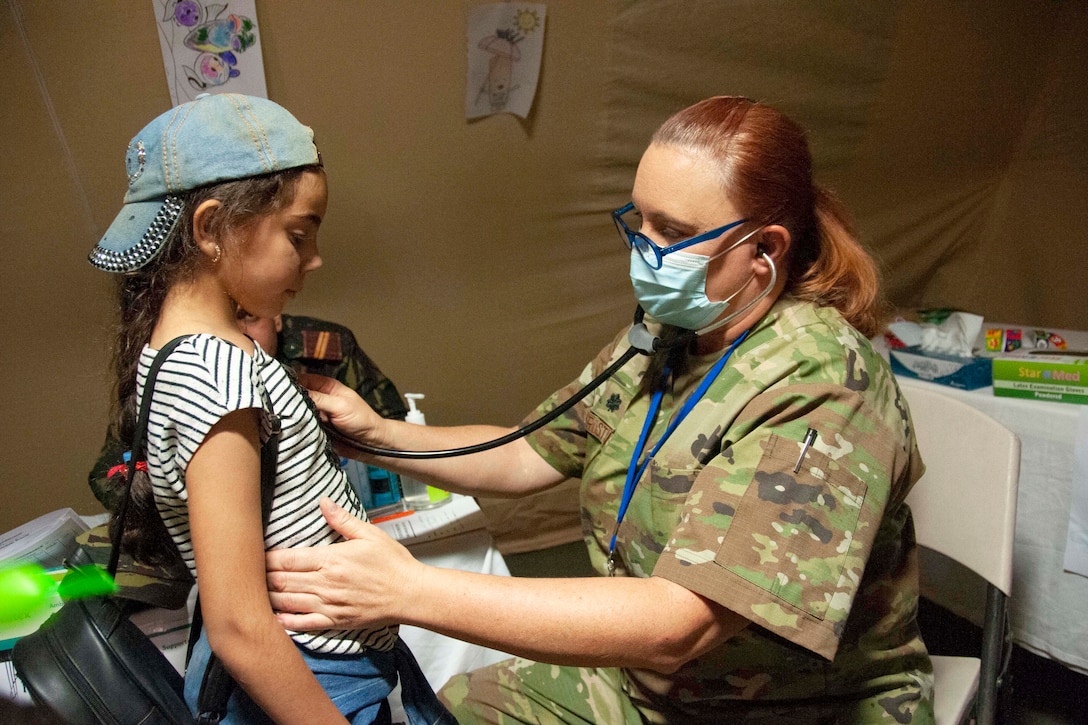 An airman examines a young patient.