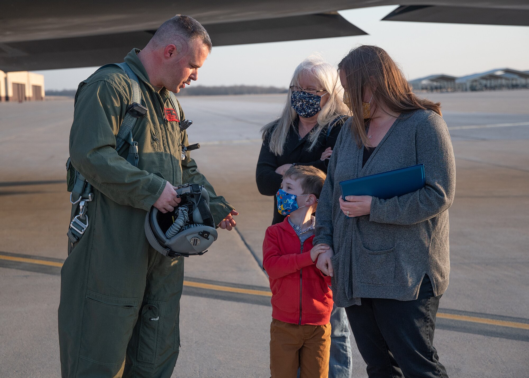 A U.S. Air Force Airman wearing a flight gear speaks with family members on the tarmac at Whiteman Air Force Base, Missouri.