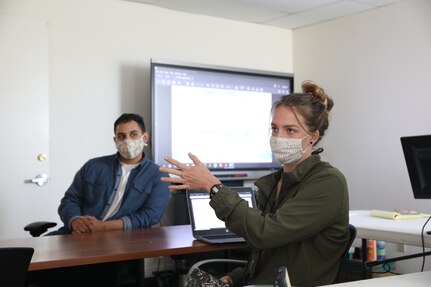 Annie Voigt of Naval Surface Warfare Center (NSWC) Corona Division’s Acquisition and Readiness Department discusses potential solutions with her data science teammates during the Navy’s Hack the Machine prize challenge March 22 in Norco, California.