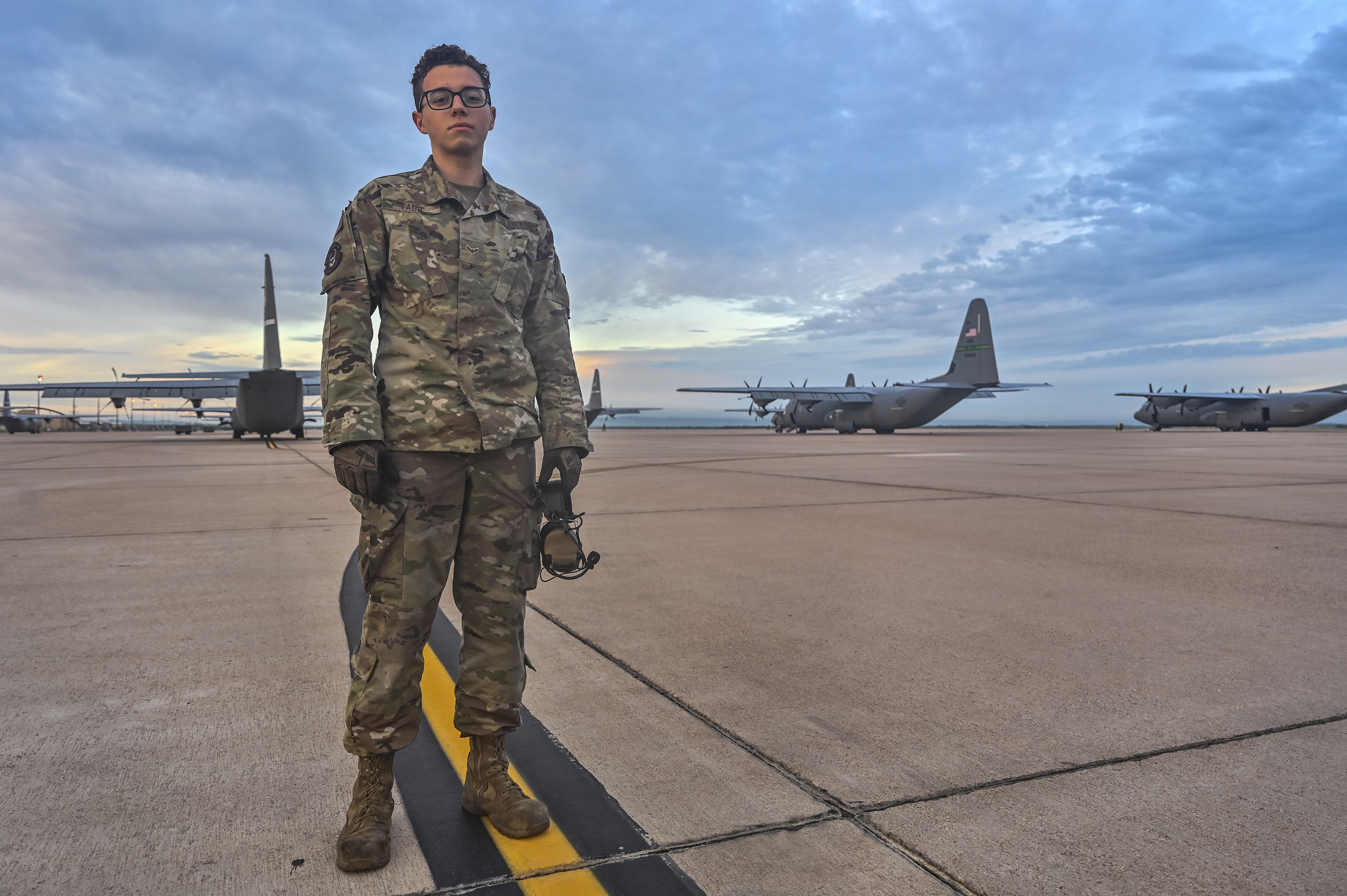 U.S. Air Force Airman 1st Class Casey Tabb, 317th Aircraft Maintenance Squadron crew chief, stands in front of dozens of C-130 airframes prior to their take-off for a class 21A Weapons Instructor Course culmination exercise at Dyess Air Force Base, Texas, June 5, 2021. Air Force crew chiefs are integral to the flying mission, ensuring safety and optimal performance for pilots and aircrews’ missions. (U.S. Air Force photo by Tech. Sgt. Alexandre Montes)