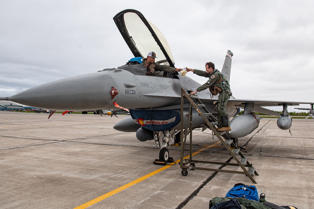 Two airmen remove items from a military aircraft.