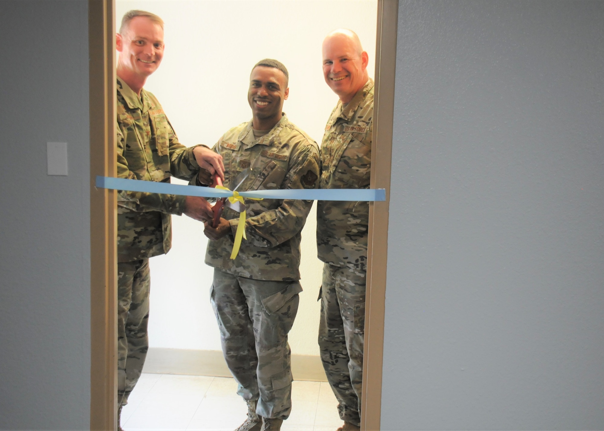 Three Airmen cut a ceremonial ribbon.