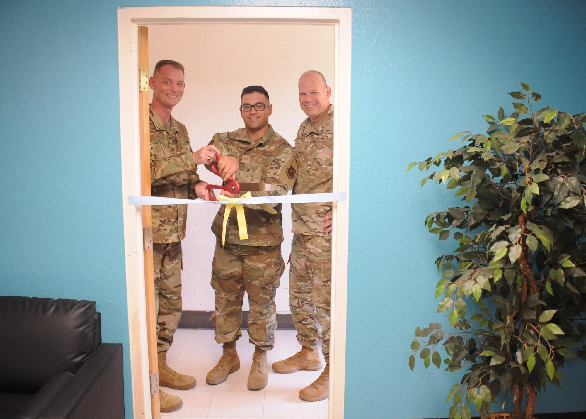 Three Airmen cut a ceremonial ribbon.