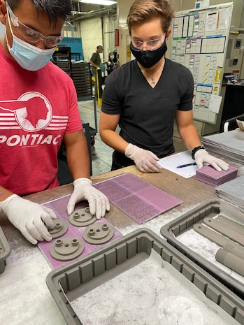 Cpl. Oscar De La Cruz (left) and Cpl. Elizabeth Patterman (right), Marines with 1st Supply Battalion, are stacking the “green” parts to prepare the items debinding and sintering at an additive manufacturing industry partner in Petaluma, California, May 26, 2021. Debinding removes a binding agent before the part goes through sintering. Sintering is the last step in the metal 3-D printing process. The parts are placed under heat to consolidate the metal powder to nearly full density. The end result is the final polymer-free metal steering wheel removal tool. (Courtesy photo)