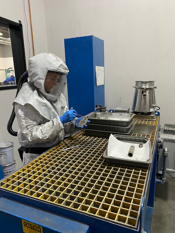 Cpl. Elizabeth Patterman, a Marine with 1st Supply Battalion, is decaking the “green” parts from the build unit in Petaluma, California, May 26, 2021. A green part is formed by metal powder held together with a binding agent. By decaking the tool, Patterman is removing any fine or residual powder from the part before it goes through the binder removal, or debinding, process. The debinding process removes the binding agent completely from the part before it goes through sintering. (Courtesy photo)