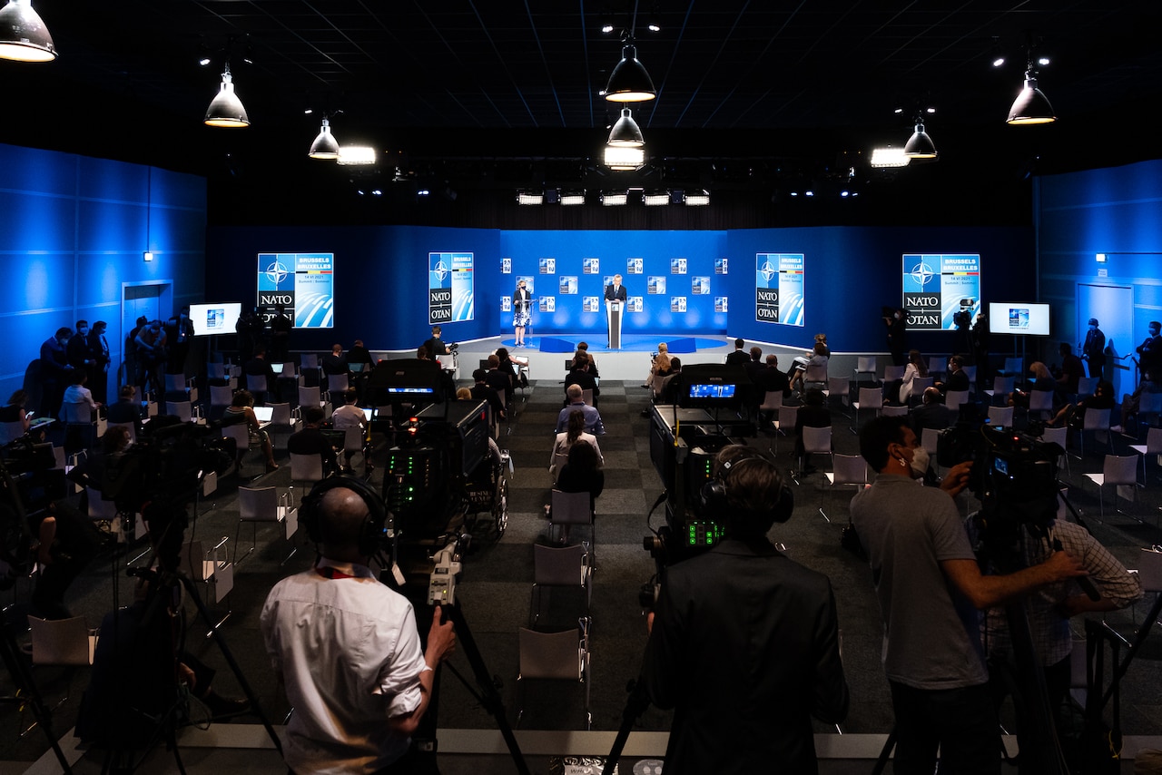 NATO leaders speak to an auditorium full of reporters.