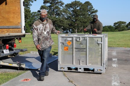 Naval Surface Warfare Center Indian Head Division (NSWC IHD) Energetics Manufacturing Department Hazardous Material Handler Darnell Hunter (left) and Hazardous Material Inspector Earl Simms (right) prepare a Joint Modular Intermodal Container (JMIC) for transport, May 18. The NSWC IHD Cartridge Actuated Devices/Propellant Actuated Devices (CAD/PAD) enterprise was notified there was an impact to a U.S. Marine Corps MV-22B attached to the Presidential Helicopter Squadron (HMX-1), May 17. Due to the impact, the aircraft was grounded at a deployed location and submitted an emergency order for several CADs. The unique route in transit from the home location of HMX-1 to the deployment location indicated a stopover at NSWC IHD would be more advantageous compared to standard ground shipment. Through coordination with NSWC IHD leadership, an MV-22B landed at the command’s helipad on the morning of May 18, where a pallet of replacement assets was waiting to be loaded onboard.