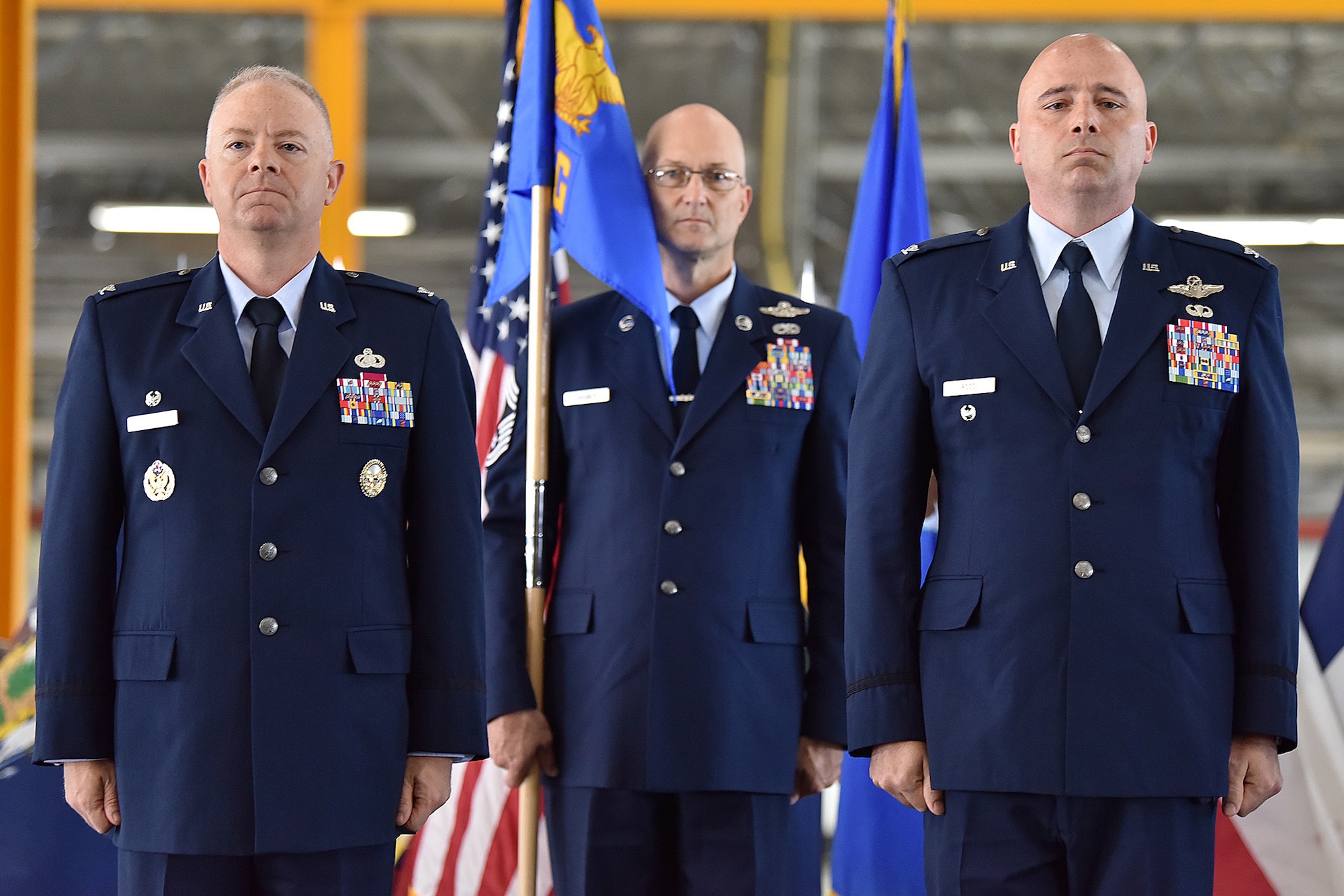 Col. Tyler Schaff, 316th Wing and installation commander, left, Col. John Ross, 316th Operations Group commander, right, and Chief Master Sgt. Harold Kruger, 316th Operations Group superintendent, stand at attention during a change of command ceremony June 10, 2021, at Joint Base Andrews, Md. Organizational flags were developed with color arrangements and symbols unique to each particular unit. A change of command is a military tradition that represents a formal transfer of authority and responsibility for a unit from one commander to another. (U.S. Air Force photo by Senior Airman Daniel Brosam)