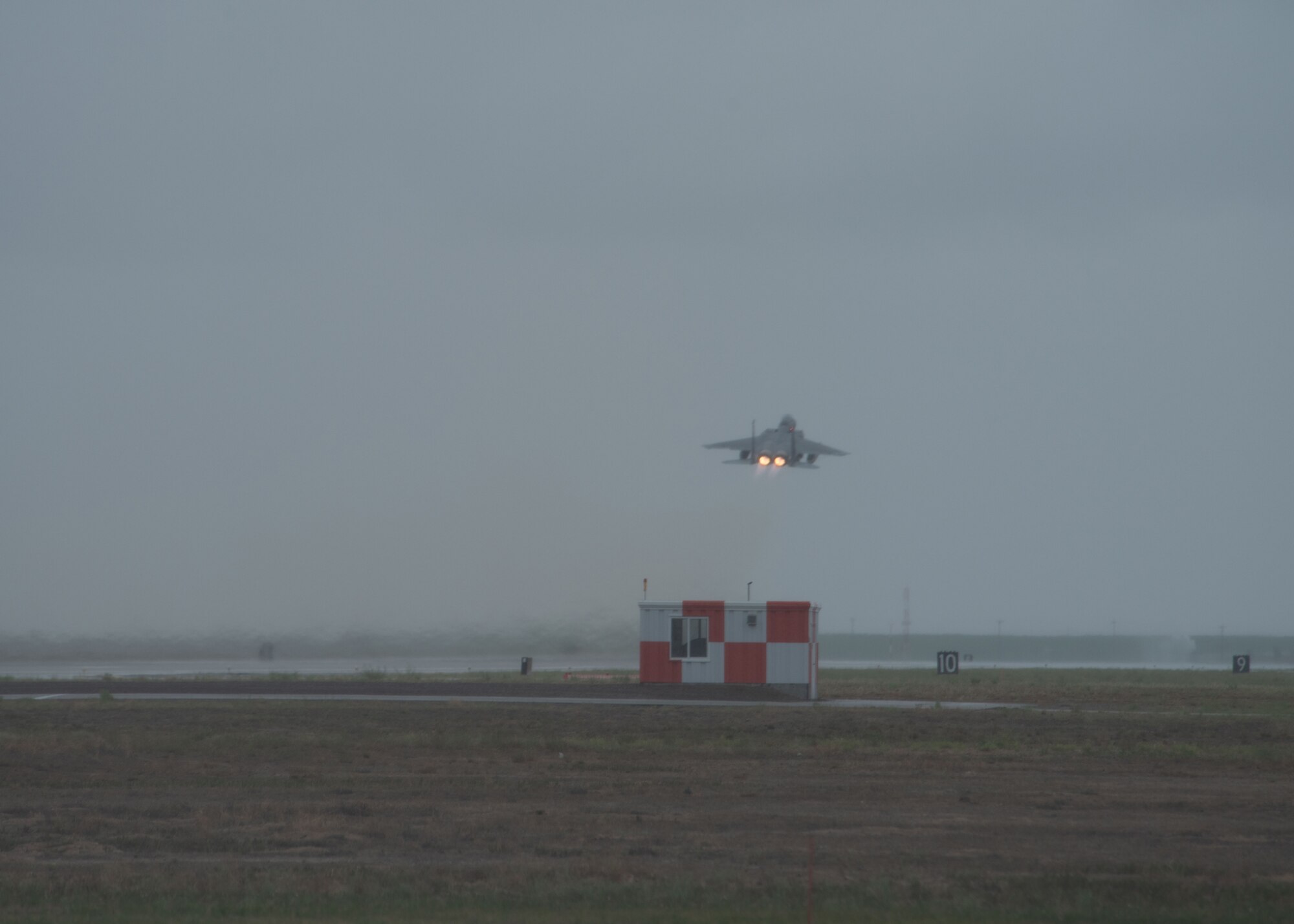 A F-15 jet aircraft takes off from the flight line runway.