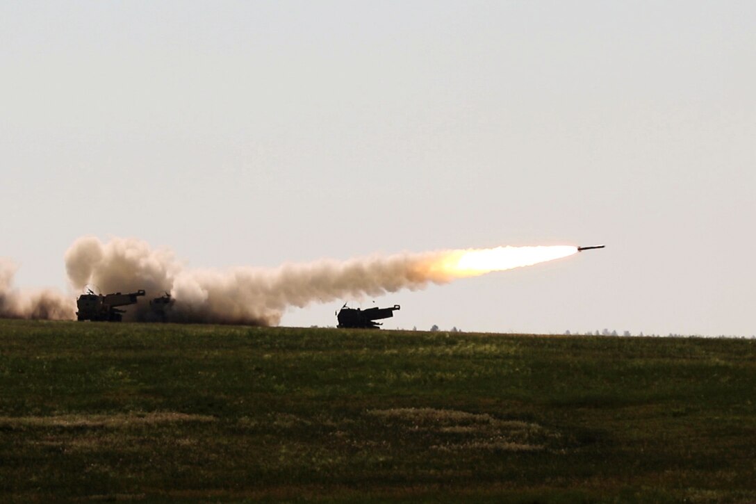 National Guardsmen fire a rocket in a field.