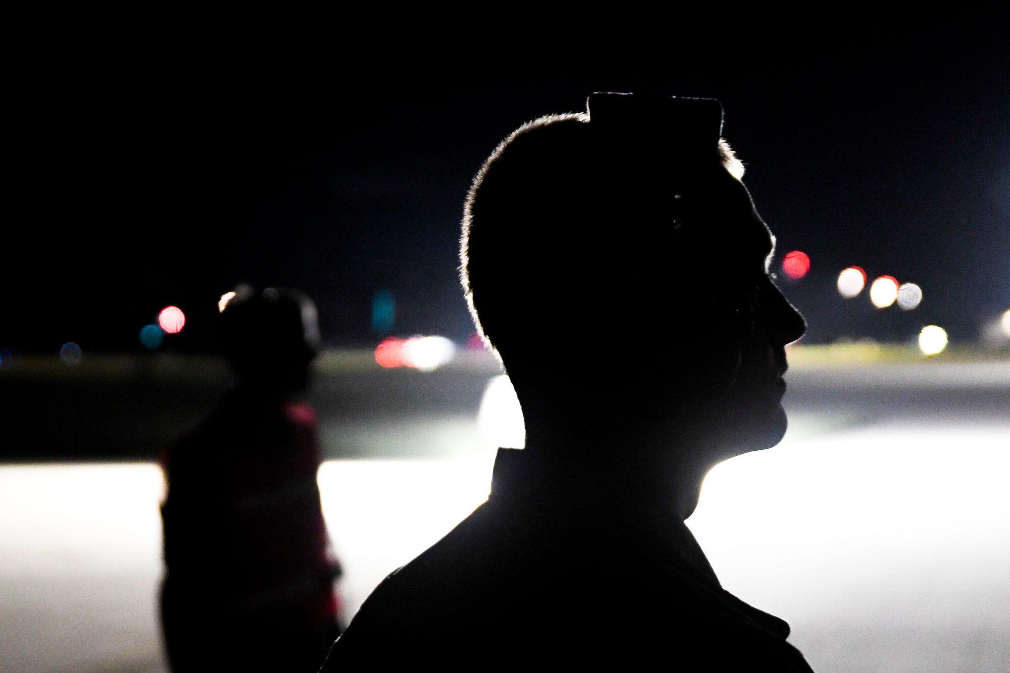 A photo of two airmen standing on the flight line at night